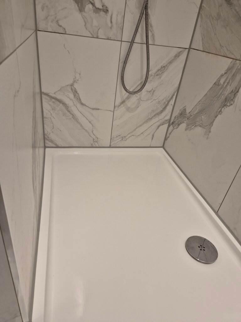 Clean colour-matched silicone after a cut out and reseal in a hotel bathroom