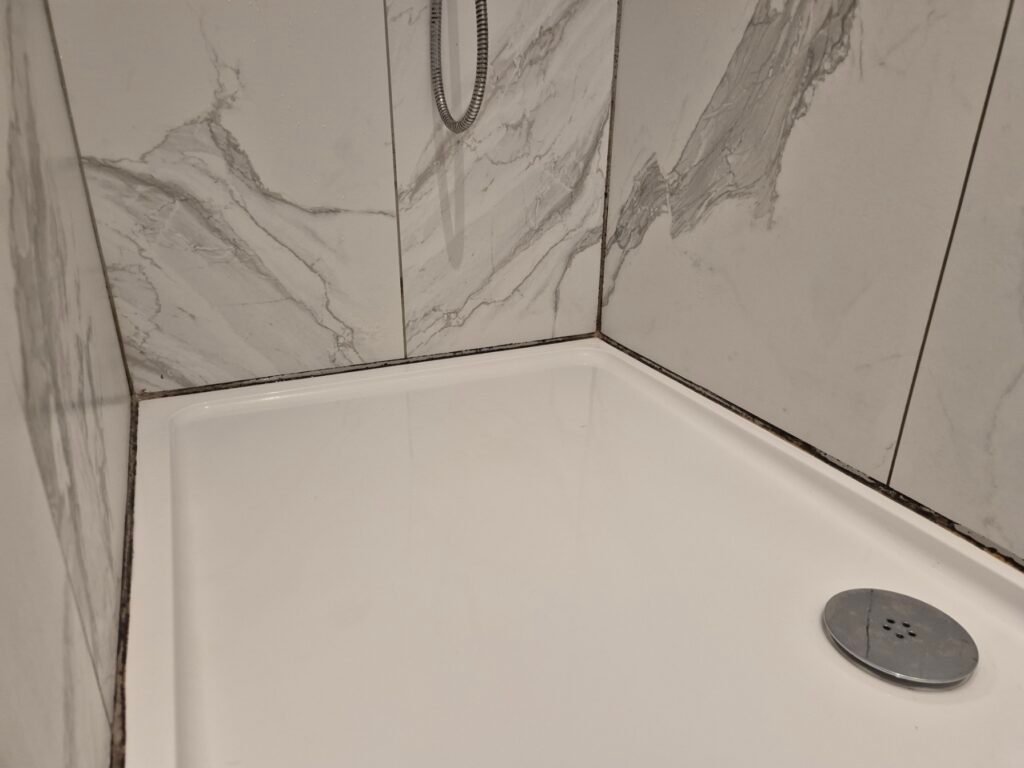Black mouldy silicone in a bathroom before a cut out and reseal